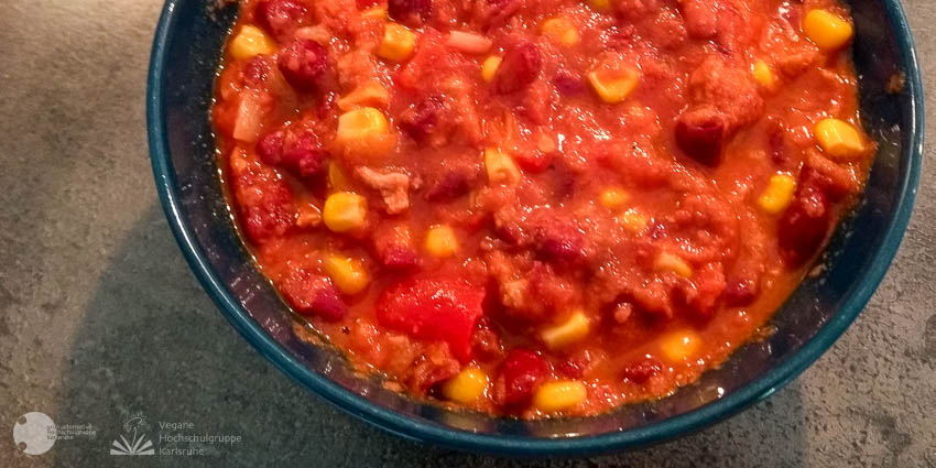 Dunkelrote Bohnen, Mais, Tomaten und Sojagranulat in Tomatensoße sind in einem Schüsselchen.