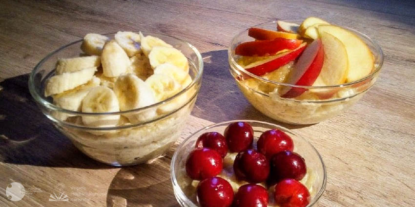 Drei Glasschälchen mit Milchreis garniert mit einemal Kirschen, einmal Apfelschnitzen und einmal Bananenscheiben class=