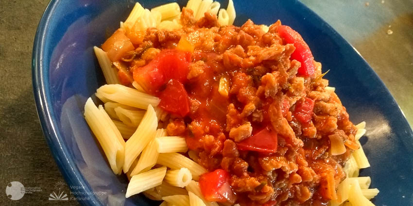 Penne mit roter Bolognese auf einem blauen Teller.
