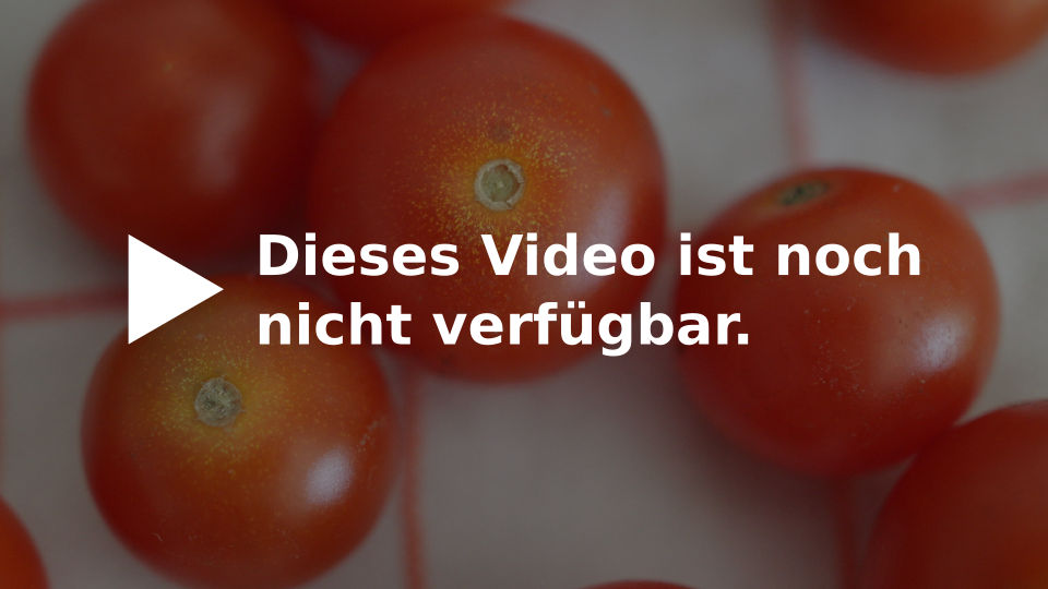 Weißer Text "Dieses Video ist noch nicht verfügbar". Im Hintergrund liegen Tomaten auf einem rot gestreiften Geschirrtuch.
